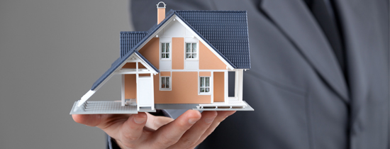A person holding a model of a house in their hand.